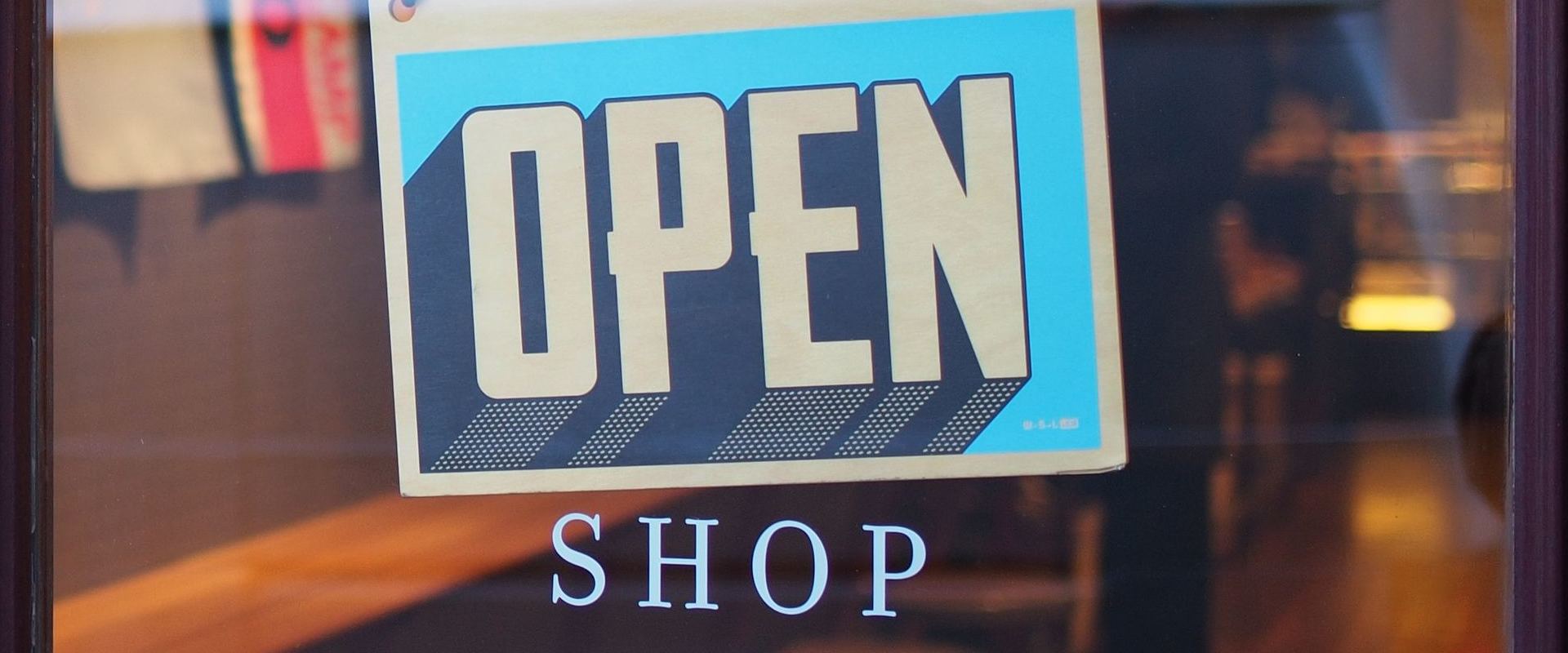 Open sign in a retail shop front window representing the creation of a remarkable retail shopping experience