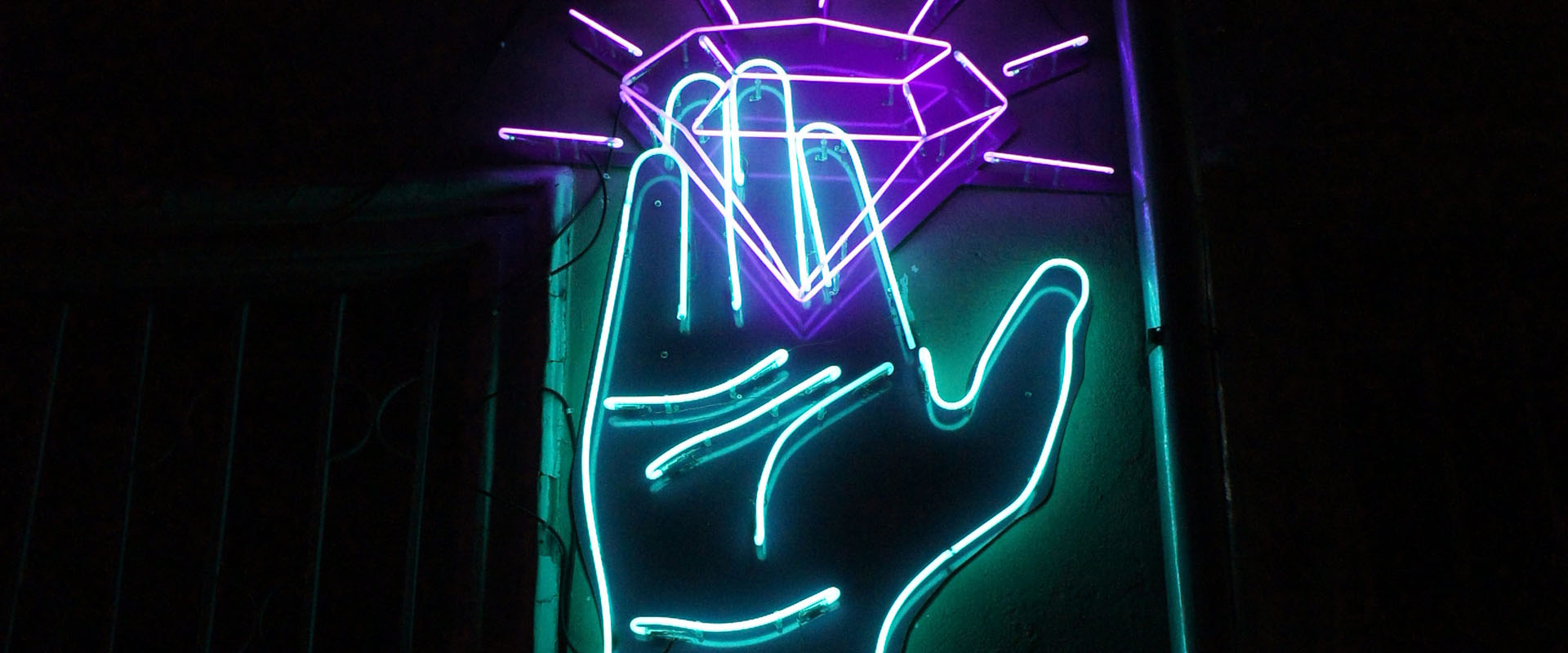 Neon sign of a hand capturing a diamond representing the brilliant basics